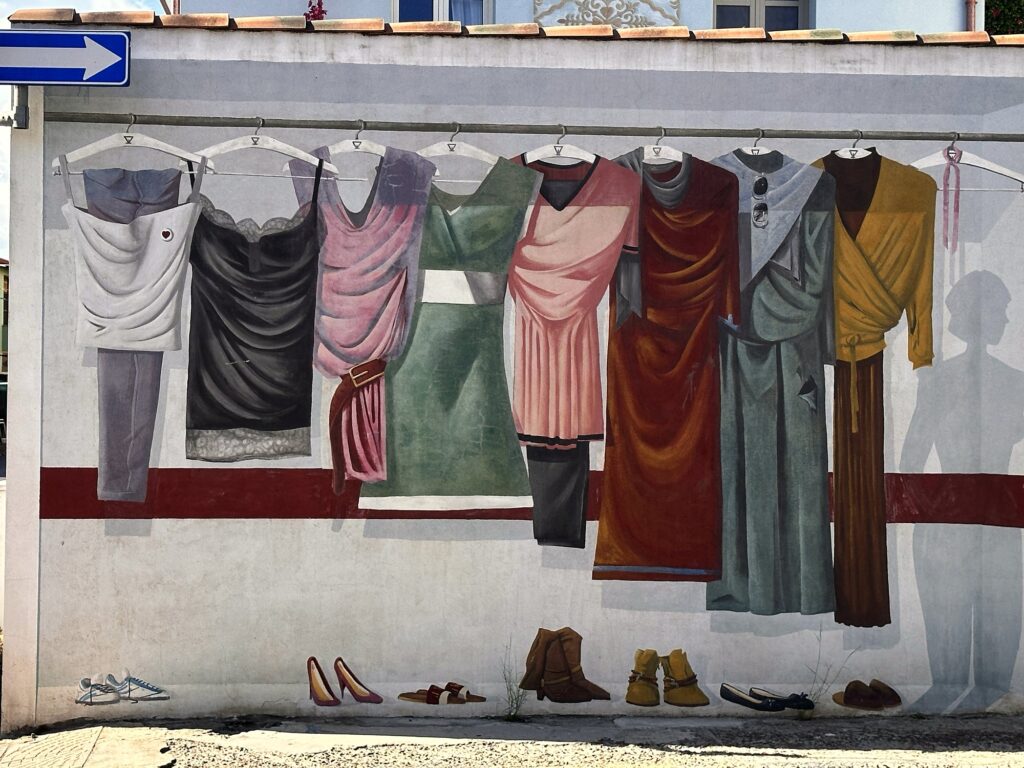 Murale con abiti femminili appesi alle grucce e scarpe allineate a terra