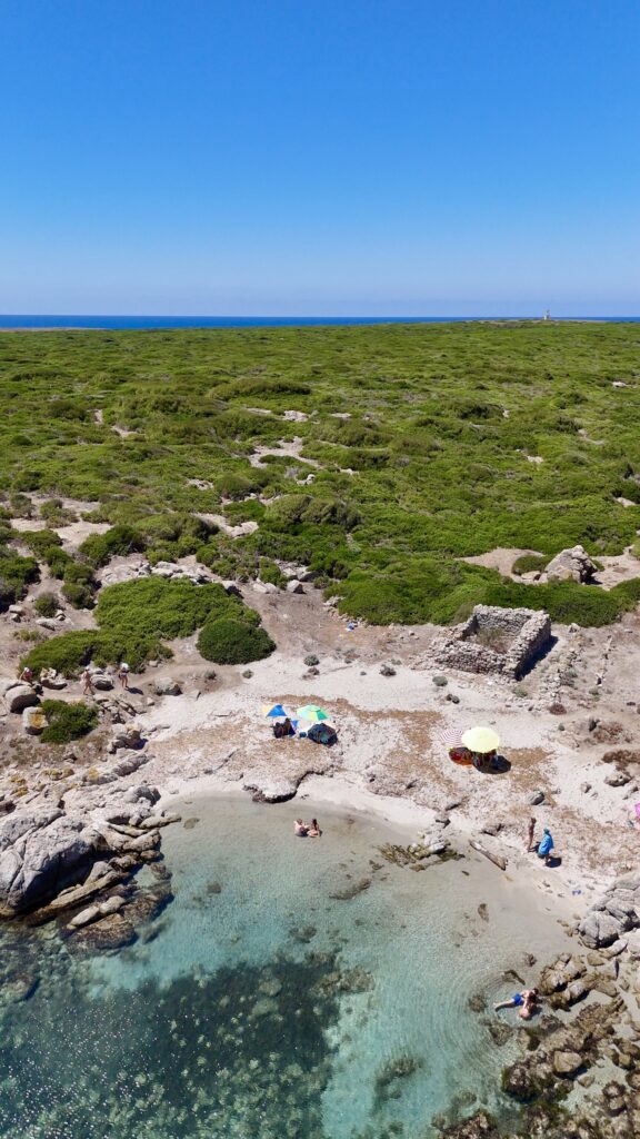 Costa bassa con rocce chiare e acqua turchese, e un'insenatura sullo sfondo