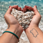 Piccoli granelli di quarzo bianco e colorato della spiaggia di Is Arutas con il mare turchese sullo sfondo