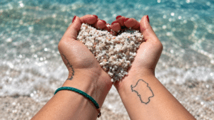 Piccoli granelli di quarzo bianco e colorato della spiaggia di Is Arutas con il mare turchese sullo sfondo