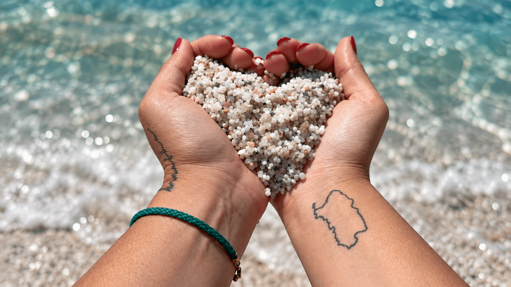 Piccoli granelli di quarzo bianco e colorato della spiaggia di Is Arutas con il mare turchese sullo sfondo
