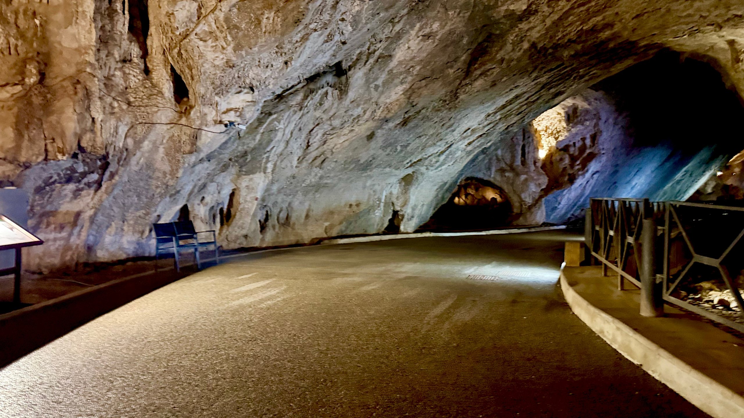 Tratto ampio della galleria con una panchina e un pannello informativo lungo la strada