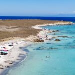 Spiaggia principale dell'Isola di Mal di Ventre vista dal drone, con ombrelloni sulla sabbia bianca e acqua turchese