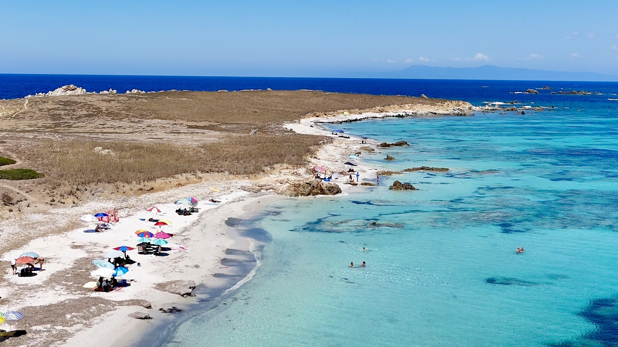 Spiaggia principale dell'Isola di Mal di Ventre vista dal drone, con ombrelloni sulla sabbia bianca e acqua turchese